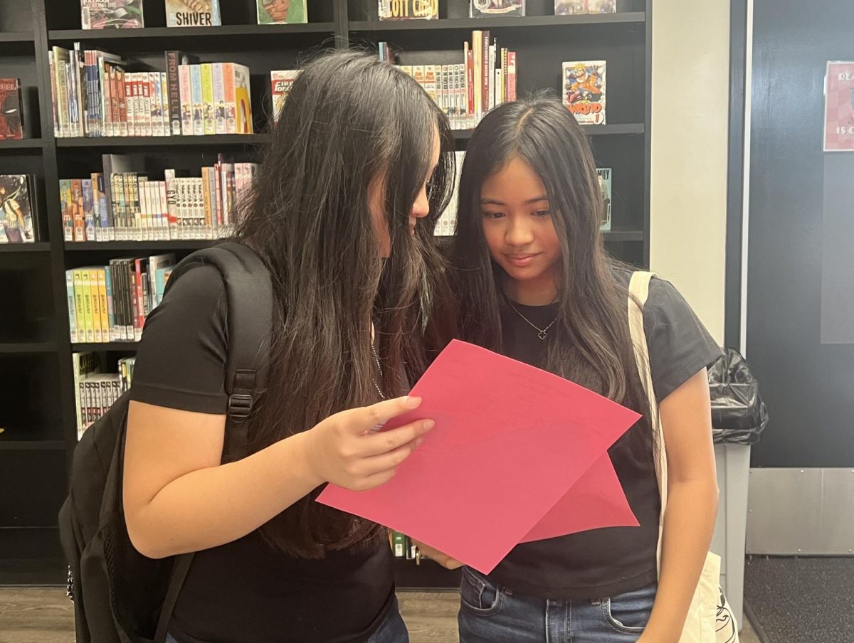 Sophomores Julianne Brie Tubiera (left) and Kaylee Arielle Velasco compare their class schedules after making their final stop in the library on Monday, Aug. 5, during Lancer Days registration.