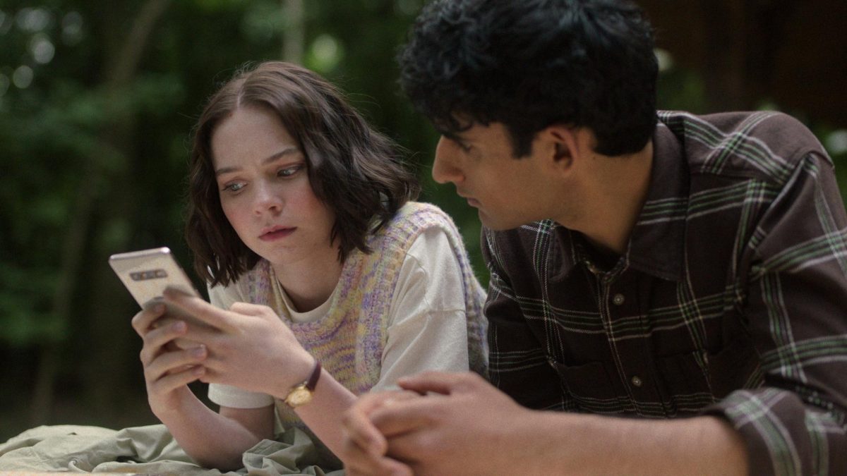 Emma Myers plays Pippa Fitz-Amobi (left), who goes on her smartphone to analyze a 5-year-old murder investigation in Episode 2 with her friend, Ravi Singh, played by Zain Iqbal.