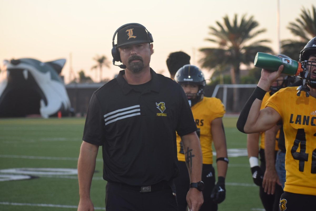 New head football coach Fred Gambrell walks toward the sideline with his players during the game against Buena Park High School on Friday, Aug. 30.