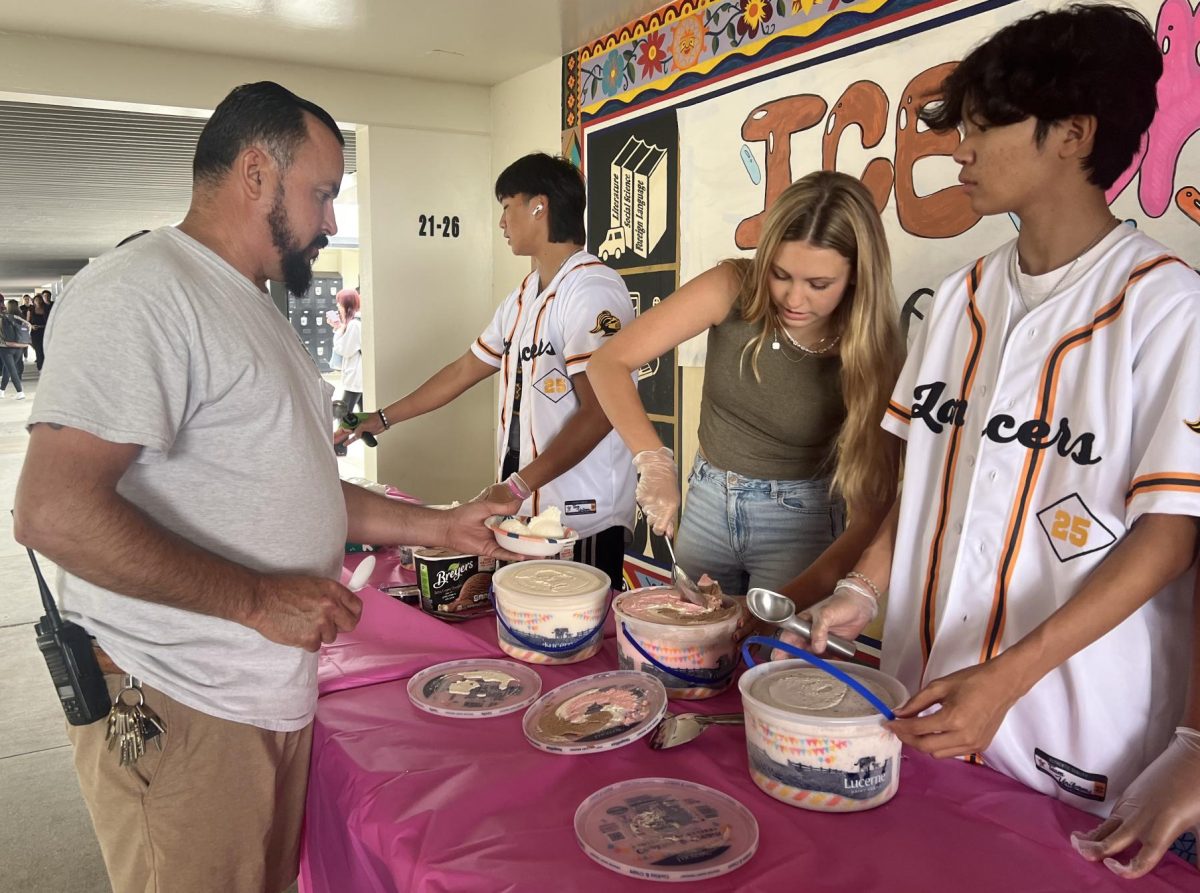 Custodian Fernando Serna (left) holds out his bowl of vanilla ice cream for Associate Student Body [ASB] member Rielynn Brimmer to fill with Neapolitan-flavored ice cream in the breezeway outside the main office between Rooms 20 and 8 during lunch on Friday, Sept. 20. The ASB was offering such cool treats to faculty and staff.