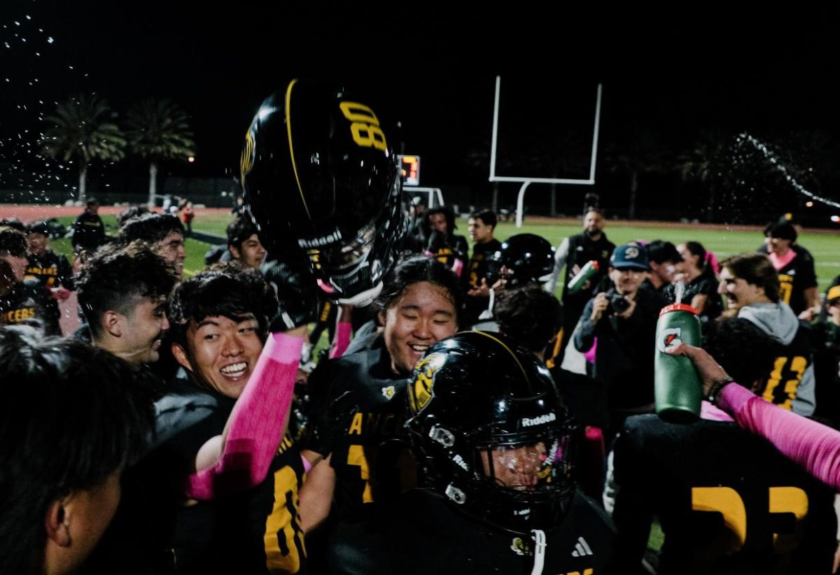 Wide receiver and linebacker senior Avery Koo (left) holds up his helmet in celebrating the Lancers’ first win of the season, a 33-3 blowout over Valencia Tigers on Friday, Oct. 18, at Buena Park High School stadium.