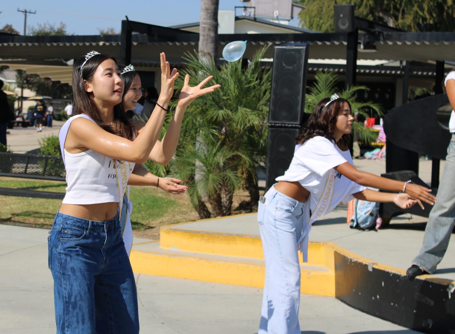 Homecoming princess senior Scarlett Chang (left), with her tiara and sash on, positions to catch the water balloon as part of the court game on Monday, Sept. 30, during break in the quad.