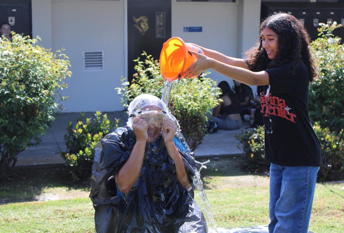 Freshman Sally Henriquez (right) dumps a bucket of slime on Link Crew leader junior Jasmine Diaz between the 20s and 40s wings during lunch on Wednesday, Oct. 10. The Slime-a-Leader event, which was hosted to build freshman connections, drew 35 participants and more who spectated.