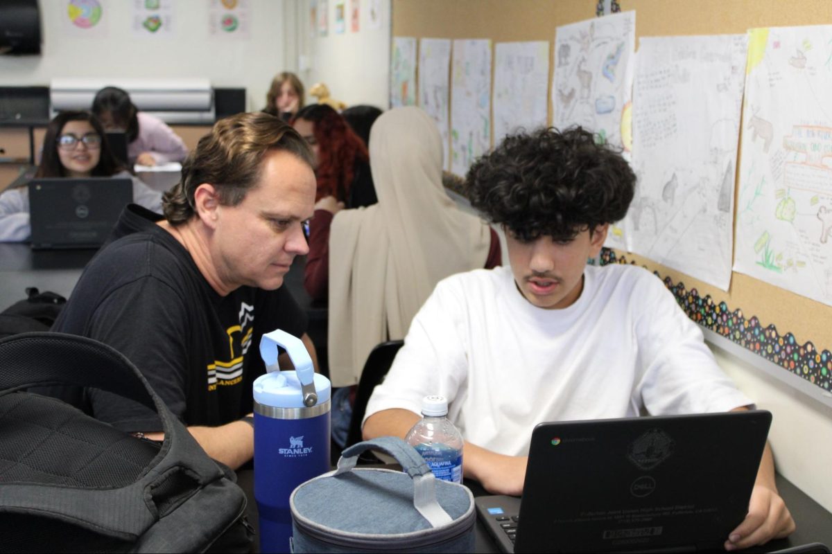 New science teacher Aaron Eide helps freshman Osama Ibrahim with opening his Chromebook to access his Biology exam during sixth period on Friday, Oct. 18.