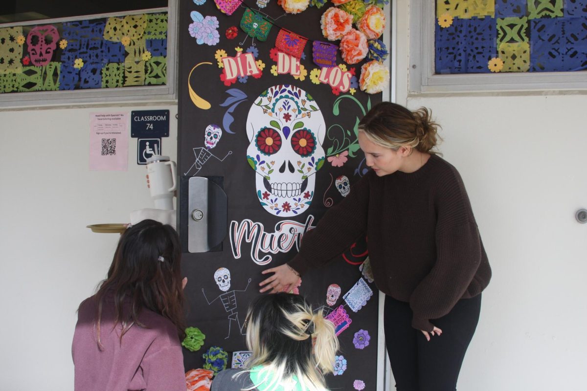 In honor of Dia de Los Muertos, senior Savannah Pruitt (right) decorates the door of Spanish teacher Cindy Ruiz’s classroom with symbols and items that represent the Day of the Dead on Wednesday, Oct. 30, during second period.