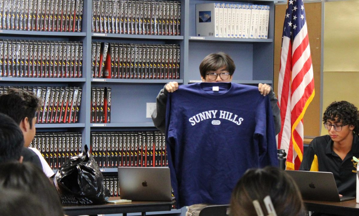 Junior class president Kevin Hur (right) holds up the Class of 2026 sweatshirt to receive feedback during the first Student Senate meeting of the 2024-2025 school year on Tuesday, Oct. 22, during fourth period in the Lyceum. Meetings are planned to be held on the first Tuesday of every month to discuss past events as well as future ones. 