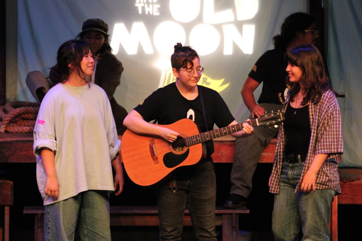 Senior Connor Woolley (center) plays the guitar with junior Christine Choi (left) and senior Katie Handley (right) standing beside her during rehearsals for “The Old Man and the Moon” on Wednesday, Oct. 30. Woolley, Choi and Handley play Matheson; Boatswain two, Solomon and Rebel one; and Llewellyn, respectively. 