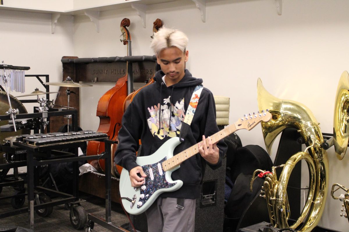 Junior Kai Liwanag plays an electric guitar during lunch on Thursday, Nov. 14, in Room 191. Liwanag, who played “Santa Tell Me,” was among those auditioning for the choir’s Sounds of the Season concert, scheduled for Friday, Dec. 6, in the Performing Arts Center.