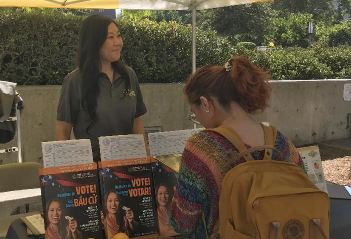 A voter picks up a pamphlet at the Orange County Registrar of Voters information booth, set up on the University of California, Irvine, campus on Thursday, Oct. 10.