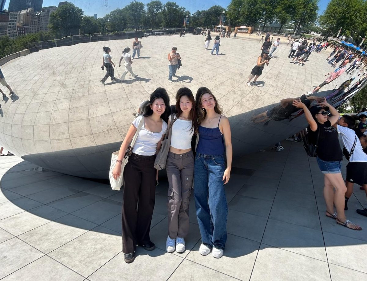 Senior Faith Jung (center) takes a picture with her friends in front of The Bean sculpture at Millennium Park on July 10 during a field trip to Downtown Chicago.