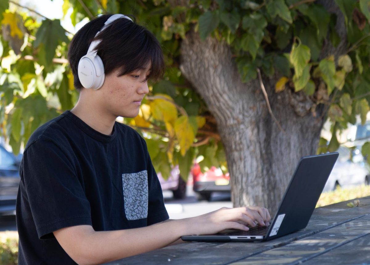 Senior Kayden Kim listens to a podcast on Spotify as he works on homework outside his fourth period class Friday, Nov. 22.