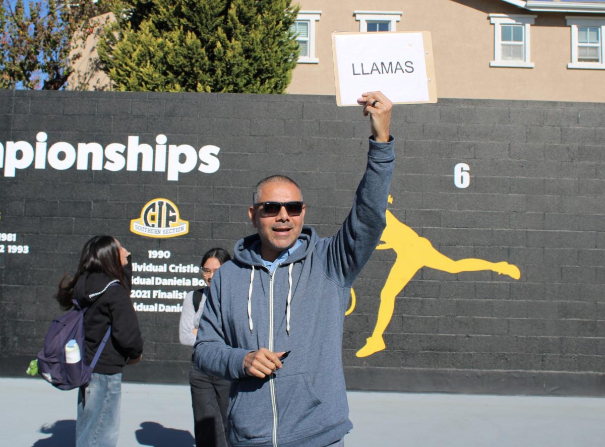 Spanish teacher Christian Llamas holds up a clipboard with his last name to help students in his second-period class meet in front of his classroom’s designated spot – tennis court No. 6 – during the fire drill on Tuesday, Jan. 14. 