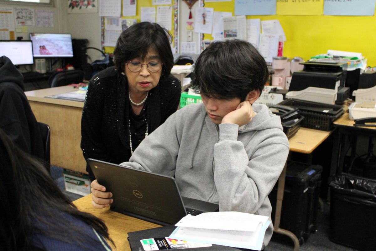 World Language teacher Esther Lee (left) helps junior William Kim with writing his journal project in Room 15 on Wednesday, Feb. 5, in his Korean 3 class. For the 2025-2026 school year, an honors option will be offered.