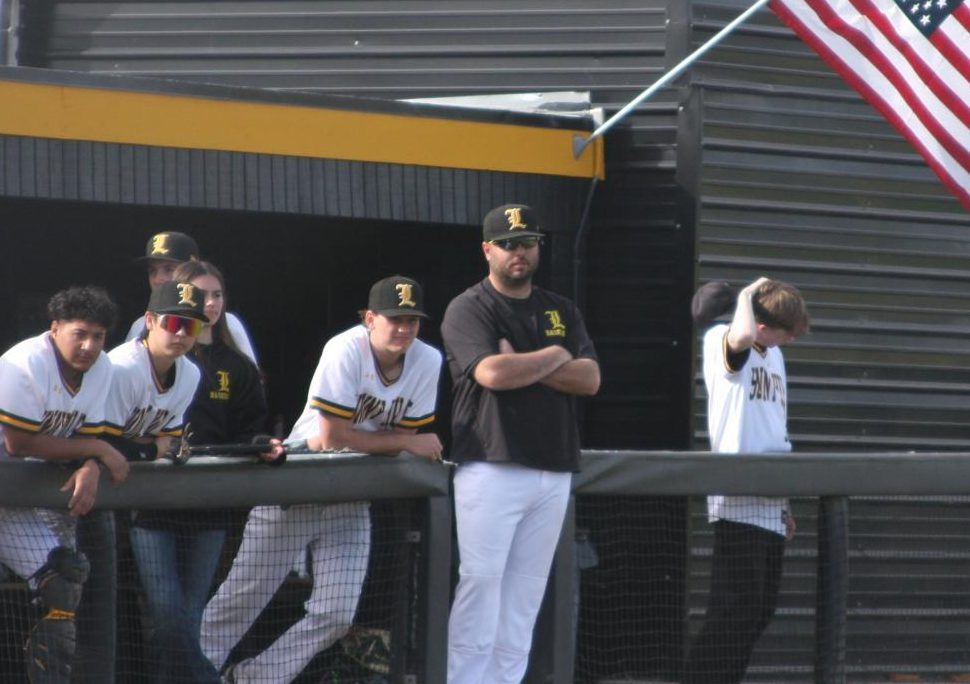Boys baseball coach Dylan Kuhn (center) stands by the dugout with players as he carefully watches the baseball game against Sonora High School at the Sunny Hills baseball field on Monday, March 10.