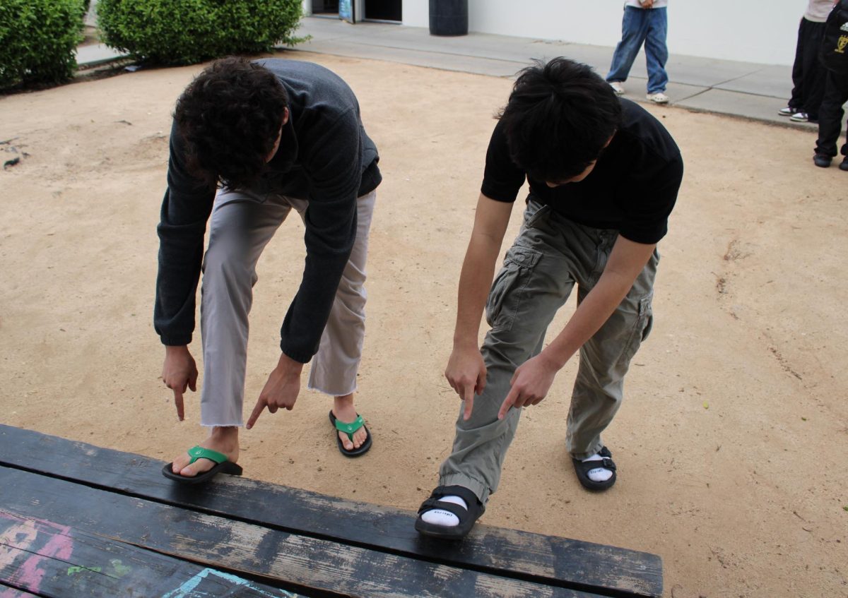 Senior Lucas Saab (left) and junior Jake Sueki point at their flip flops in front of Room 138 on Wednesday, March 26, during lunch. 