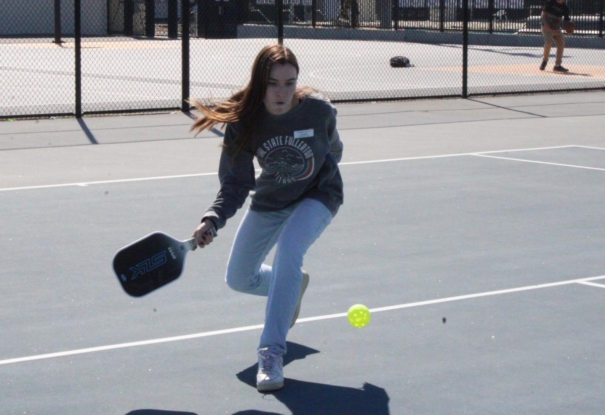 Jacquelyn Dunlap crouches down to hit the pickleball with her paddle on Tuesday, Feb. 25, during lunch on the tennis courts.