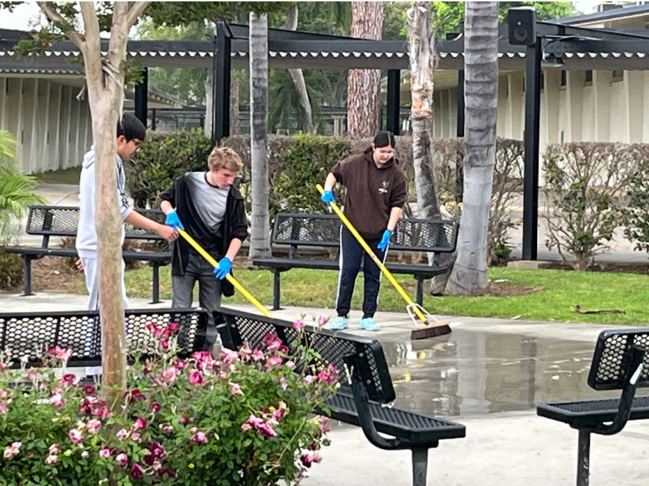 Then-sophomore Ayden Currier (left) and then-junior Kayla Choe mop and clean the drawings and messages in chalk left by the senior pranksters in the quad on May 24, 2024. Custodians also worked to clean other parts of the campus.
