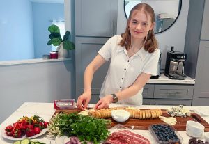 Senior Sophia Kiker crafts a spring- themed charcuterie board for a pre-prom party order on April 23, 2024, for her business.