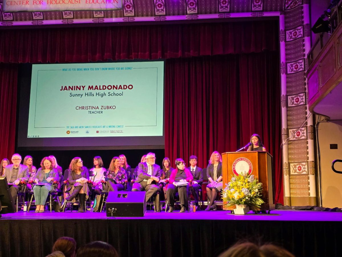 Sophomore Janiny Maldonado (right) reads out her essay, “Carrying What Matters,” during the 26th Annual Holocaust Art and Writing Contest awards ceremony, standing behind the podium on Friday, March 14, at Chapman University in Orange.