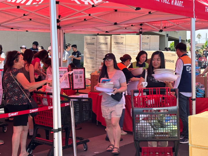 Under a red tent with the supermarket’s logo on it, employees help customers sign up for H Mart’s loyalty program and distribute gifts to those who purchased over $50 worth of merchandise on Aug. 9.