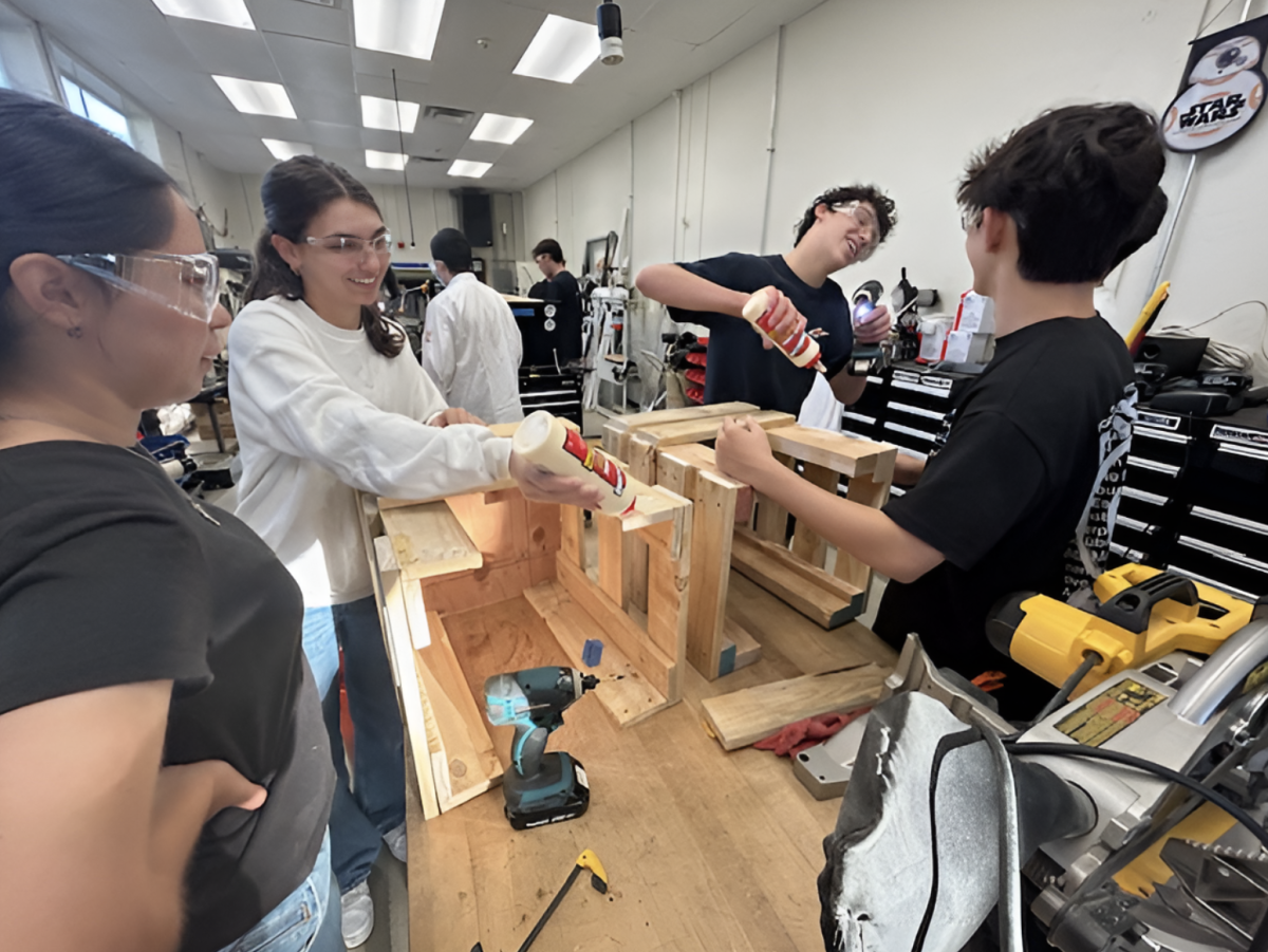 Then-seniors Isabella Reyes (left), Hannah Saab, Lucas Saab and Malekai Yun assemble their community service projects in the workshop in Room 301 on Friday, Nov. 22, during zero period.