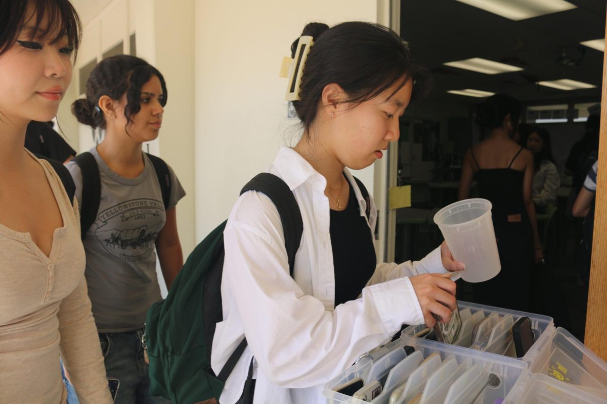 Sophomore Shizhen Jin places her phone in English teacher Christina Zubko’s “phone jail” outside Room 64 on Friday, Sept. 12, just before the start of sixth period.