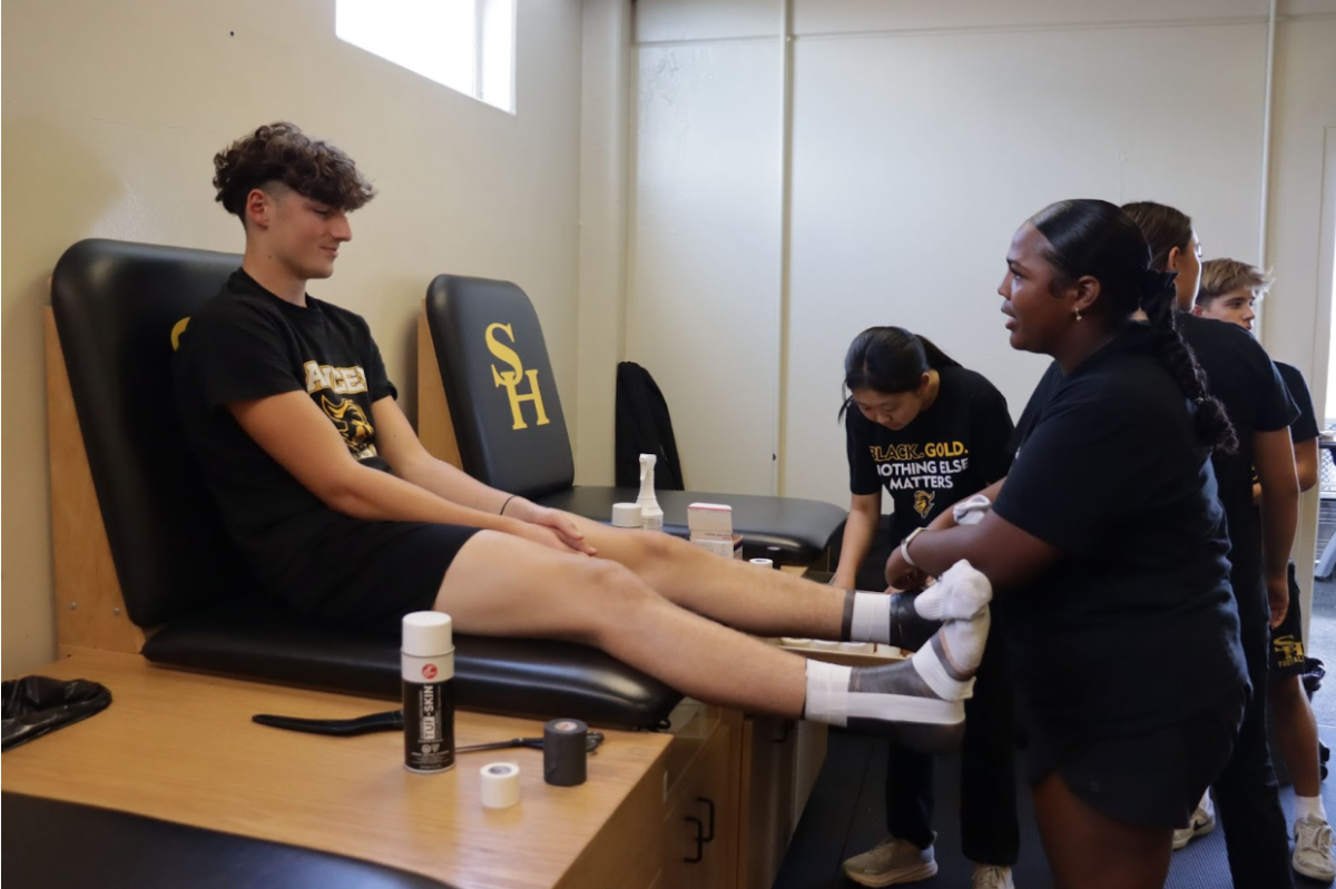 Senior Elayna Marquez (right) tapes senior Joshua Stewart’s (left) left foot in Room 141 after school on Tuesday, Sept. 2.