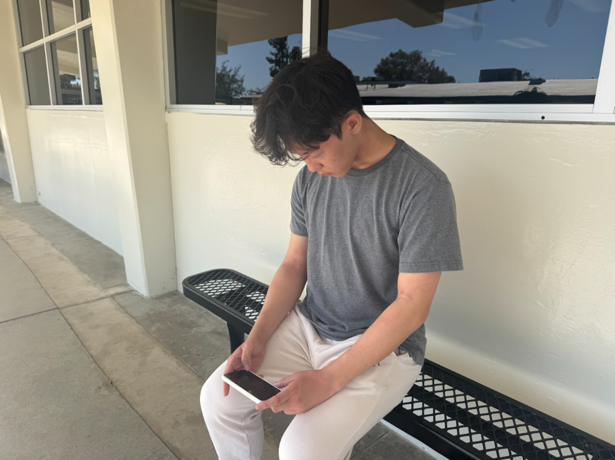 Senior Marcus Chang plays Pokémon Unite on a bench in front of Room 104 during lunch on Wednesday, Sept. 24.