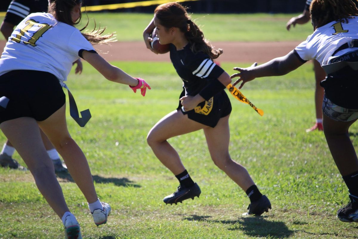 Senior rusher Sydney Kim runs with the ball in her hand to pass the opposing team’s attempt at removing her flag during the game against Whitney High School on Monday, Sept. 8.