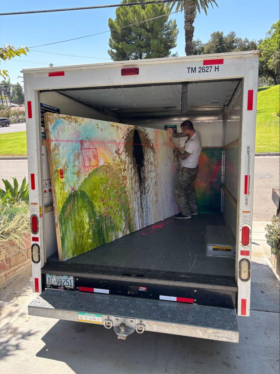 Senior Jasper Hanrahan's dad helps load the 5-foot-10-foot wood panel into a truck that moves the painting to the gallery location on Friday, Aug. 29.(Image used with permission from Jasper Hanrahan)