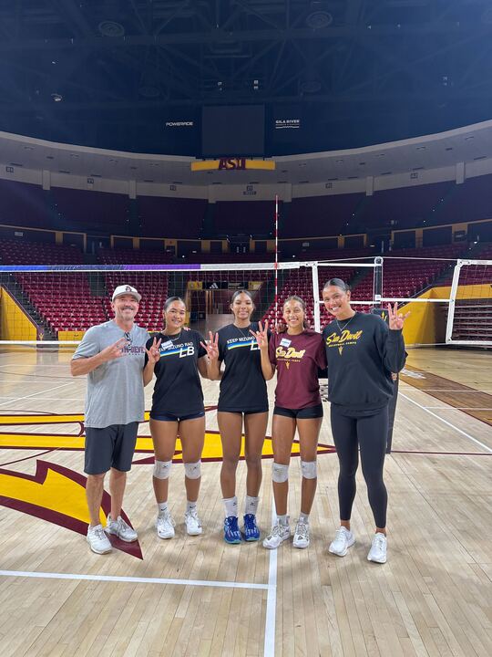 Sophomore Reagan Williams holds up the Arizona State University “Pitchfork” hand sign with coaches and teammates.