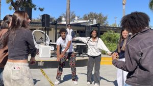 Cutline: Senior Pierrce Sandle (center) dances with other students in the quad during the DJ battle between social science teacher Marcus Reveles and athletic director Paul Jones on Thursday, October 16. 