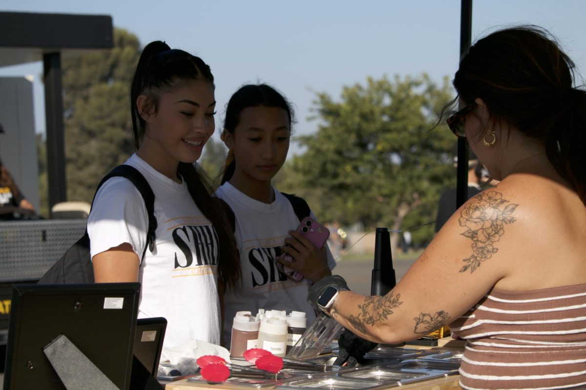 Sophomore Alissa Rubio and freshman Bella Morales order acai bowls from the Ubatuba Acai stand after school on Tuesday, Sept. 30, outside the gym.