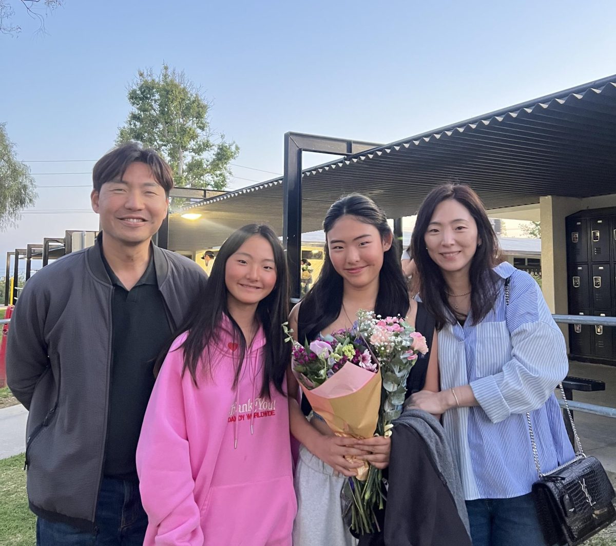 Sophomore Kaylynn Park (second from the right) smiles for a family photo in front of the PAC after her dance showcase on Saturday, April 12. 