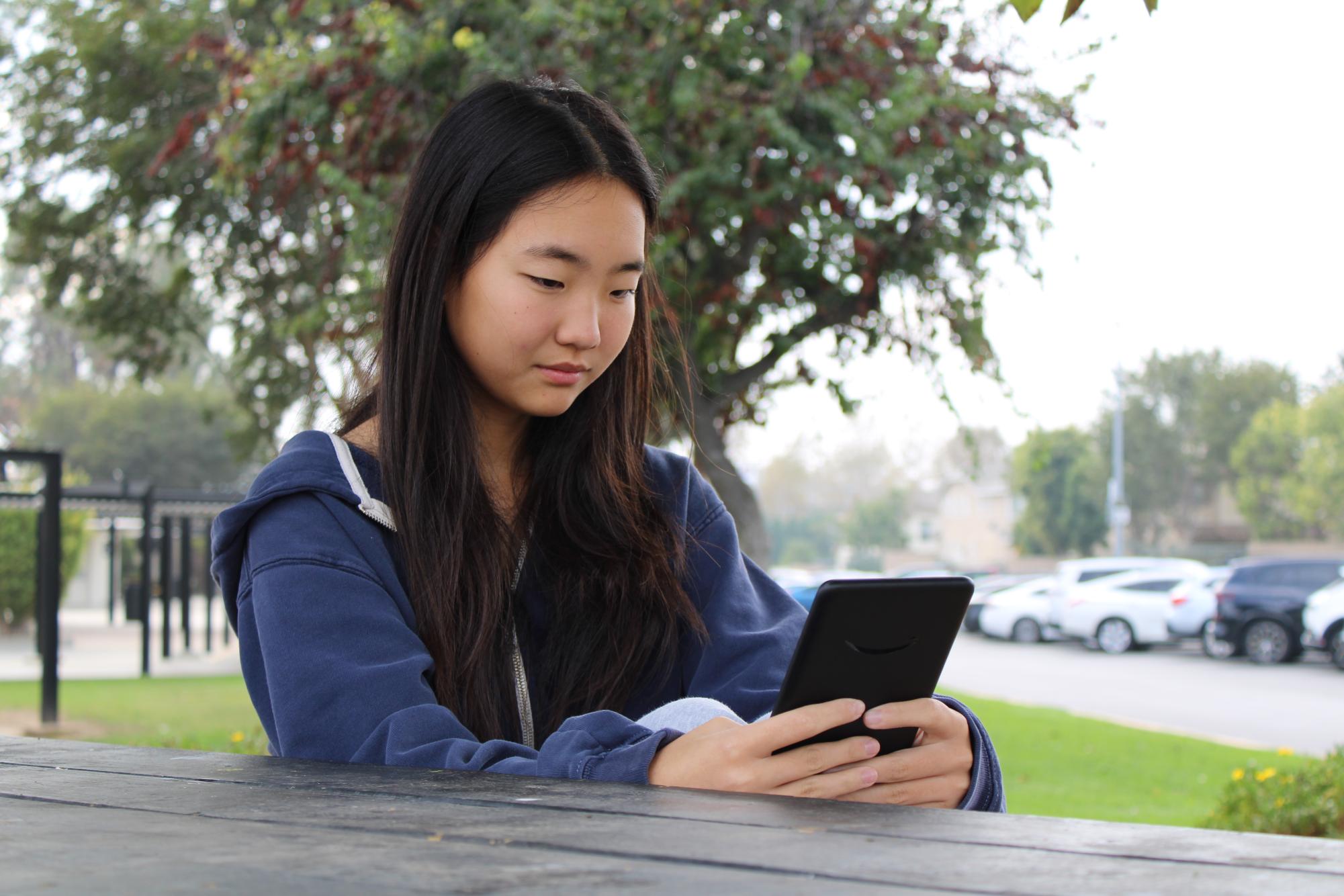 Junior Ashley Kang reads on her Kindle outside of Room 138 on Wednesday, Nov. 12.
