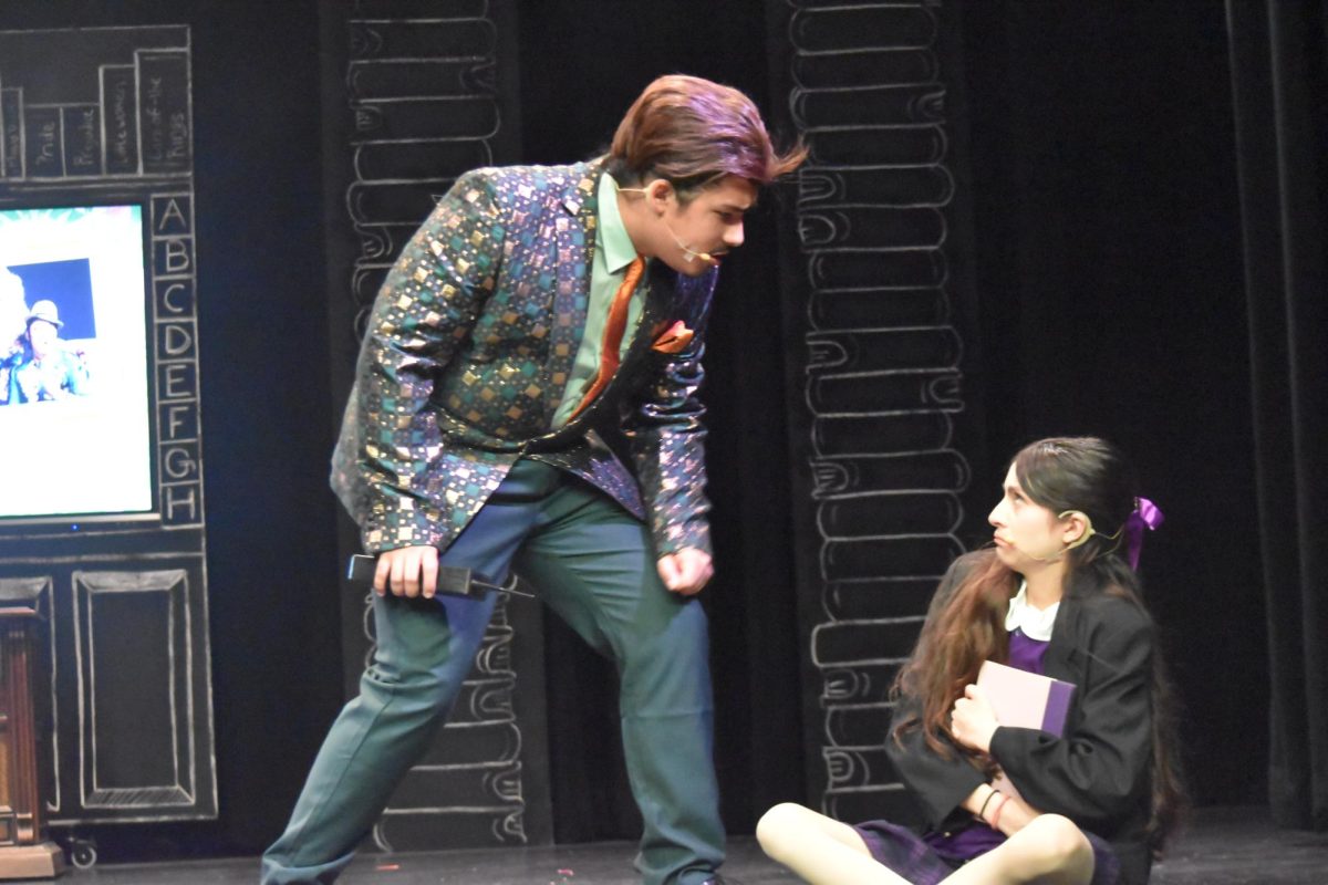 Senior Michael Olivares (left), who plays the role of Mr. Wormwood, approaches sophomore Olivia Olsson, who plays the titular role of Matilda, as she clutches her book on Tuesday, March 3, in the Performing Arts Center [PAC]. The musical will debut tomorrow at 7 p.m. in the PAC.