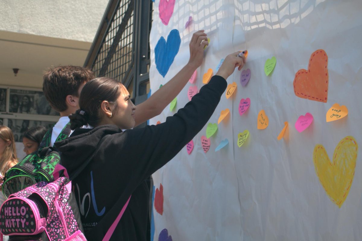 Senior Ayah Maaytah writes on a heart-shaped note near the quad on Wednesday, Aug. 13, during the first week of school.