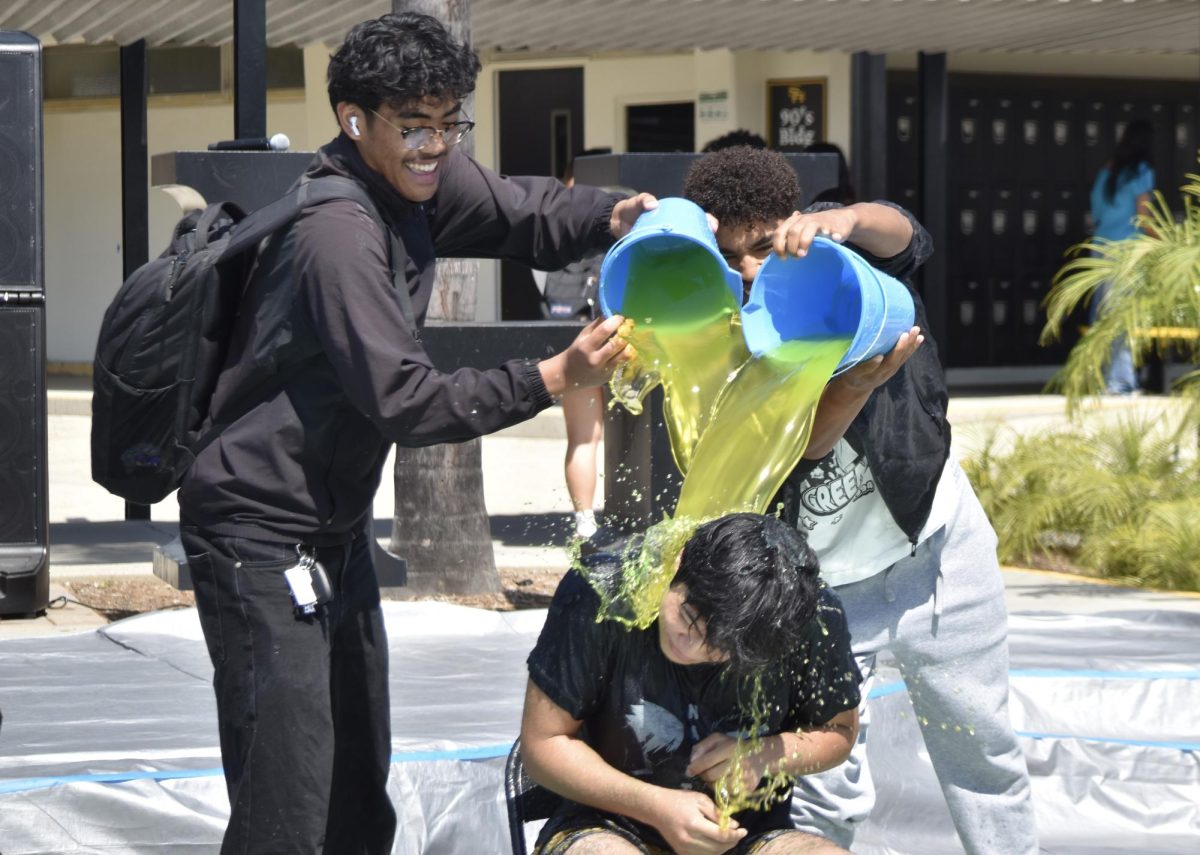 Seniors Jadyn Salud (left) and Pierrce Sandle pour slime on senior Elijah Orlino during Associated Student Body’s Slime a Senior event held at break on Thursday, April 30, in the quad.